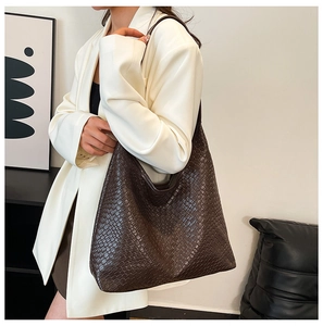 Detailed view of woven dark brown tote bag on model for a minimalist fashion style