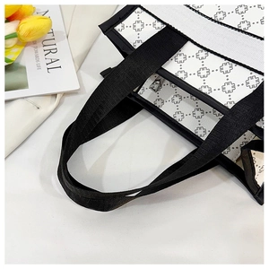 Detail of white tote bag with black clover pattern and sturdy reinforced handles