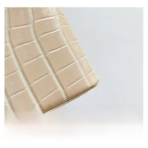 Close-up of the premium stone-textured embossed faux leather on this beige bucket bag
