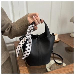 Close-up of black pebble leather bucket bag with white polka dot silk scarf detail
