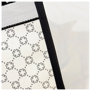 Close-up of white canvas tote bag with geometric floral pattern and black leather piping