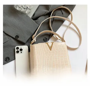Detail of cream faux crocodile texture bucket bag with gold V hardware and strap