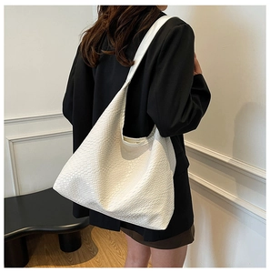 Close-up of white oversized tote bag with woven texture and wide shoulder strap