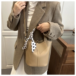 Detail of beige litchi leather bucket bag with decorative polka dot silk scarf handle