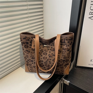 Chic leopard print tote bag with brown straps and gold metal accent in soft natural light