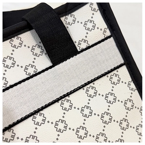 Detail of white textured leather tote with grey floral pattern and black trim stitching