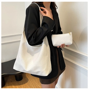 Detail of white woven texture hobo bag and matching pouch shown with a black blazer