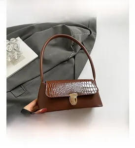 Detail showing brown crocodile pattern leather texture and golden metal lock on the bag