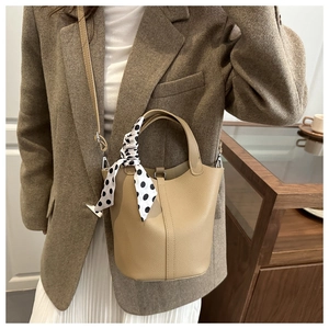 Close-up of apricot leather bucket bag featuring a polka dot silk scarf handle detail