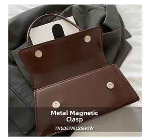Close-up of secure magnetic snap closures on the brown leather underarm handbag detail