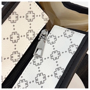 Close-up of silver metal zipper and geometric monogram pattern on luxury leather tote bag