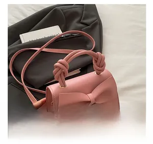 Detail of pink crossbody bag with a large decorative bow and unique knotted top handle