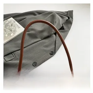 Detail showing the brown crocodile pattern texture and polished round handle of the bag