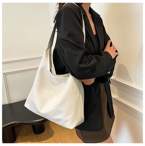 Detailed view of the woven texture and trapezoidal design of the large white tote bag