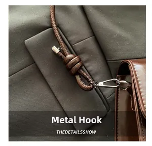 Detailed close-up of premium silver hardware hook on dark brown leather crossbody bag