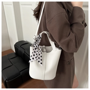 White lychee leather bucket bag with silk scarf wrapped handle shown on model
