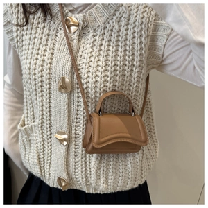 Mini borsa a tracolla in pelle opaca marrone con patta curva mostrata su un outfit da modella