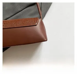 Detail showing the contrast between crocodile embossed leather and smooth brown matte finish