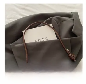 Detail of a brown vintage leather handle with elegant knot design on a French shoulder bag