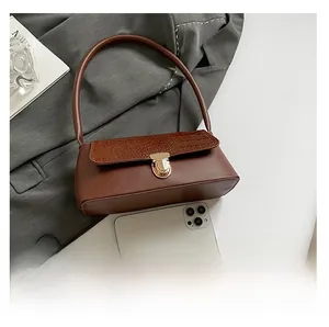 Close-up of brown leather shoulder bag with croc-embossed flap and gold clasp detail