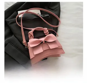 Détail du sac bandoulière rose avec grand nœud et poignée nouée au design élégant