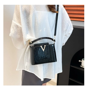 Detail of black faux crocodile skin bucket bag with gold V-logo and slim shoulder strap