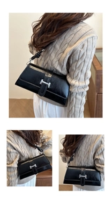 Detail of black leather shoulder bag showing the silver H buckle and knotted strap design