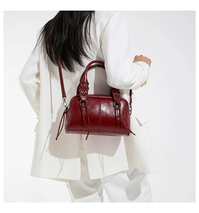Macro detail of wine red leather Boston bag with silver rings and long tassel accents