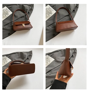 Detail view of dark brown baguette bag featuring croc-effect texture and gold metal buckle