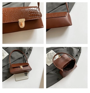 Detail view of brown faux leather underarm bag with crocodile pattern and gold buckle