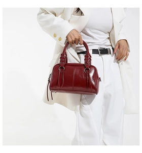Detail of burgundy leather boston bag featuring woven handles and stylish leather tassels