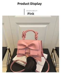Detail of soft pink handbag featuring a large bow and twisted woven handle detail