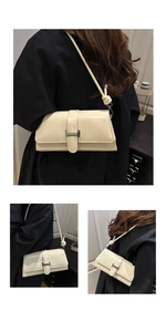 Detail of cream baguette bag with glossy leather finish and H-shaped metal buckle
