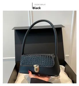 Detail of black faux leather shoulder bag with crocodile texture and gold metal lock