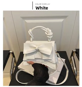 Detail of white handbag featuring a large decorative bow and woven rope handle texture