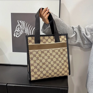 Canvas tote bag with M-letter monogram pattern and black leather straps for daily commute