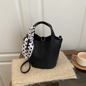 Elegant black pebble leather bucket bag with shoulder strap and stylish polka dot scarf