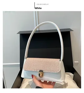 Detail of white baguette shoulder bag with beige crocodile texture and gold twist lock