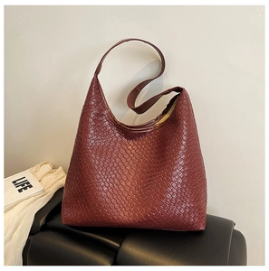 Detail of the woven texture and wide shoulder strap on a burgundy hobo tote bag