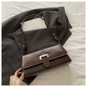 Detailed close-up of dark brown baguette bag with glossy leather and silver clasp