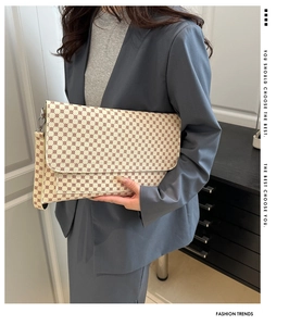 Close-up of minimalist monogram clutch with detachable strap held by model in suit