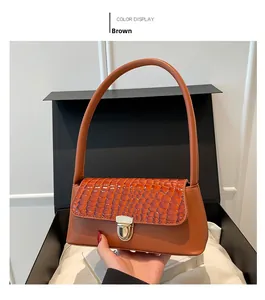 Close-up of brown baguette bag with crocodile texture detail and gold snap closure