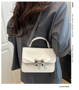 Detail of white glossy mini square bag with silver butterfly buckle and chain strap