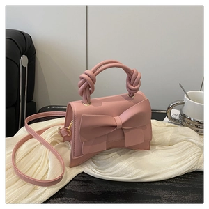 Détail d'un mini sac à main rose avec un grand noeud et une poignée nouée élégante