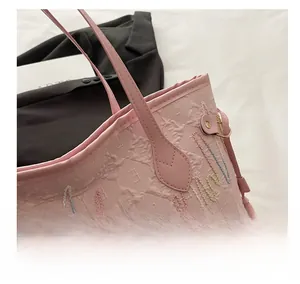Primo piano della borsa tote rosa con trama logo goffrata e ricami a onde colorate