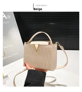Detail of beige crocodile pattern bucket bag featuring a gold V-shaped metal clasp