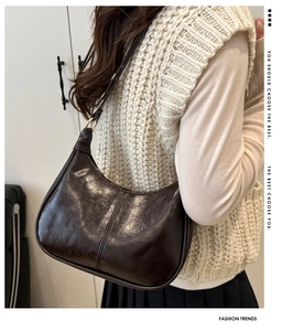 Side view of dark brown hobo bag with vertical stitching and adjustable strap on model