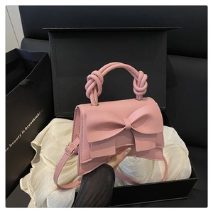 Détail du sac à main rose en cuir avec grand nœud et poignée tressée dans son coffret