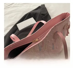 Dettaglio della cerniera dorata e del ricamo jacquard rosa sulla borsa tote
