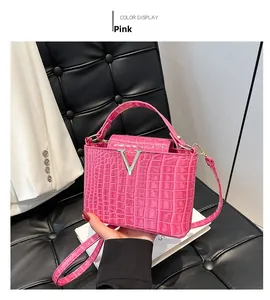 Detailed view of pink croc-effect bucket bag featuring a signature silver V-shaped clasp
